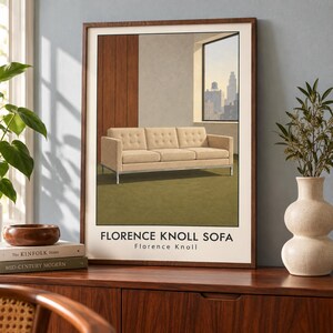 May include: A framed art print featuring a beige tufted sofa with a metal frame, set in a room with wood paneling and a city view through a window. The text FLORENCE KNOLL SOFA and Florence Knoll is printed in black at the bottom of the white border.
