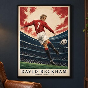 May include: A framed poster featuring a soccer player in a red jersey with the number 7 and white shorts kicking a soccer ball in a stadium. The background shows a red sky and a large sun. The text reads DAVID BECKHAM FOOTBALL LEGENDS 10.