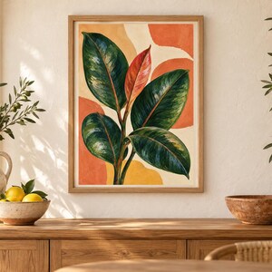 May include: A framed wall art print featuring a botanical illustration of a rubber plant with large, glossy dark green leaves and one central reddish-orange leaf, set against an abstract background of soft orange and yellow circular shapes.