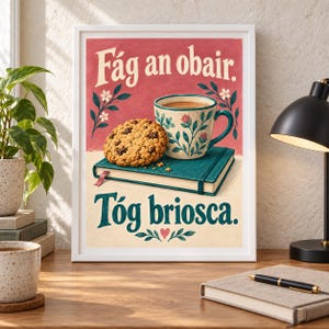 Pu&ograve; includere: Una stampa artistica incorniciata con sfondo rosso e il testo F&aacute;g an obair, e una sezione inferiore color crema con il testo T&oacute;g briosca. L'illustrazione mostra un biscotto con gocce di cioccolato su un libro verde acqua accanto a una tazza.