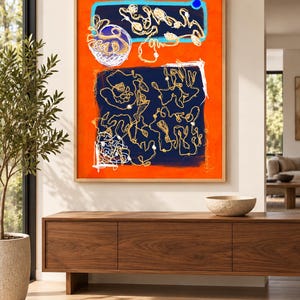 May include: A rectangular framed wall art piece featuring a vibrant orange background with two large dark blue rectangular sections. The artwork contains intricate white and gold line drawings, abstract shapes, and a small solid blue circle.