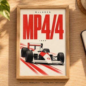 May include: A framed poster featuring a white and red McLaren MP4/4 Formula 1 race car with the number 12. The text reads McLaren, MP4/4, and 1988. The design includes red motion lines on a white background, presented in a light wood frame.