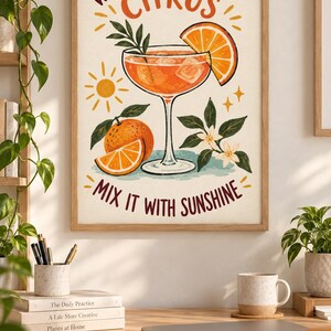 May include: A framed wall art print featuring a cocktail glass filled with orange liquid and ice, garnished with an orange slice. The text reads "WHEN LIFE GIVES YOU CITRUS MIX IT WITH SUNSHINE" alongside illustrations of a sun, oranges, and blossoms.