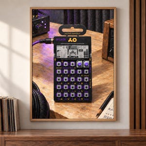 May include: A black pocket operator arcade synthesizer featuring a grid of sixteen buttons with purple accents, a small monochrome LCD screen displaying digital graphics, and a purple audio cable connected to the top left input port.