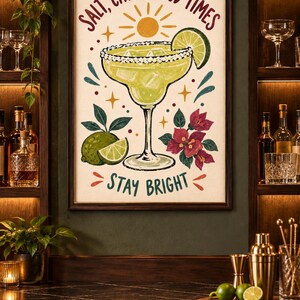 May include: A framed wall art print featuring a margarita in a glass with a salted rim, a lime wedge, and ice cubes. The text reads SALT, CITRUS, GOOD TIMES and STAY BRIGHT. The illustration includes a yellow sun, lime fruit, and pink flowers.