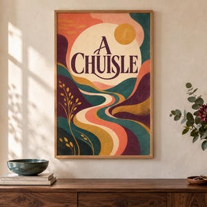 Puede incluir: Una l&aacute;mina de pared rectangular enmarcada que muestra un paisaje estilizado con colinas onduladas en tonos verde azulado, morado y naranja. Un gran c&iacute;rculo crema contiene el texto A CHUISLE en letras moradas oscuras sobre un sol amarillo.