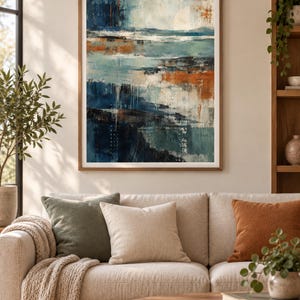 Op de afbeelding: Een ingelijste abstracte muurkunstprint met een gelaagde compositie van diep marineblauw, groenblauw en gebrande oranje tinten met gestructureerde penseelstreken en witte accenten, gepresenteerd in een eenvoudige houten lijst.