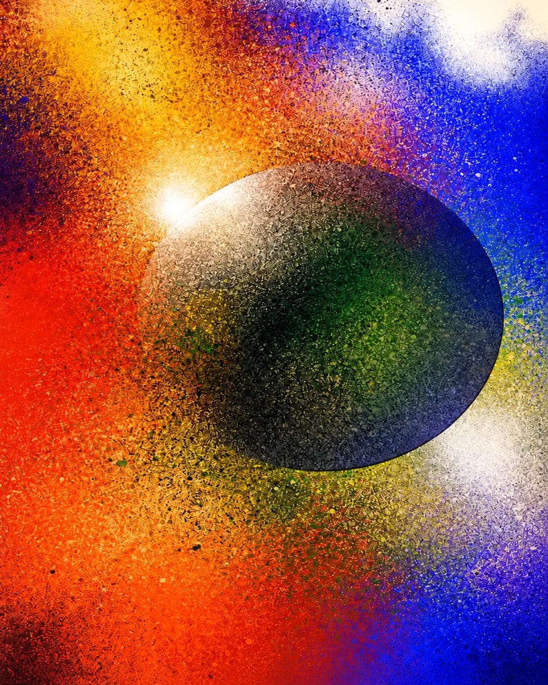 Op de afbeelding: Een cirkelvormig donkergrijs object met een getextureerd oppervlak is gecentreerd tegen een levendige achtergrond van spuitverfkleuren. Het omliggende veld vertoont een gradi&euml;ntovergang van felrood en oranje naar gele, blauwe en paarse spikkels.