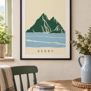 Pu&ograve; includere: Una stampa artistica incorniciata con un'illustrazione stilizzata delle isole Skellig in Irlanda. L'opera mostra montagne frastagliate verde scuro e una capanna di pietra a forma di alveare su sfondo crema e mare azzurro, con il testo KERRY.