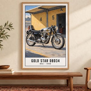 May include: A framed wall art print featuring a 1956 BSA Gold Star DBD34 motorcycle parked in front of a yellow garage building with the numbers 4 and 5 visible. The text at the bottom reads GOLD STAR DBD34 BSA 1956 in a clean black font.