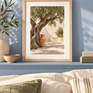 May include: A framed wall art print featuring a gnarled olive tree with green leaves, a terracotta amphora, and a stone wall in a sunlit courtyard. The print is housed in a light-toned wooden frame with a white mat, displayed on a blue shelf.