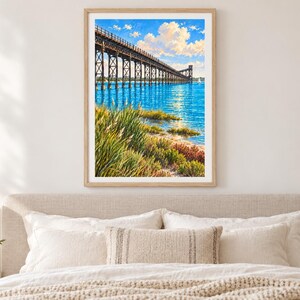 Peut inclure: Une peinture de paysage encadr&eacute;e repr&eacute;sentant un long pont &agrave; chevalets en bois s'&eacute;tendant sur une eau bleu vif. Le premier plan pr&eacute;sente de hautes herbes vertes et une v&eacute;g&eacute;tation c&ocirc;ti&egrave;re sous un ciel rempli de nuages blancs et un petit voilier.