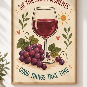 May include: A framed wall art print featuring a glass of red wine, a cluster of purple grapes, green leaves, a yellow sun, and small red hearts. The text reads SIP THE SWEET MOMENTS at the top and GOOD THINGS TAKE TIME at the bottom in dark lettering.