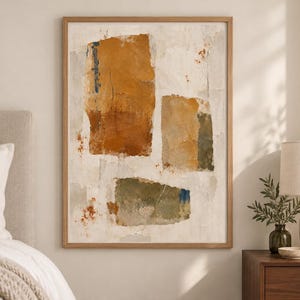 May include: A framed rectangular wall art piece featuring an abstract composition of three distinct, textured blocks in shades of ochre, burnt orange, and muted olive green against a neutral, off-white background with subtle paint splatters.