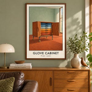 May include: A framed art print titled GLOVE CABINET by Finn Juhl, depicting a wooden cabinet with open doors revealing a stack of drawers in a gradient of blue, yellow, and orange colours, set on a wheeled base against a light green wall.