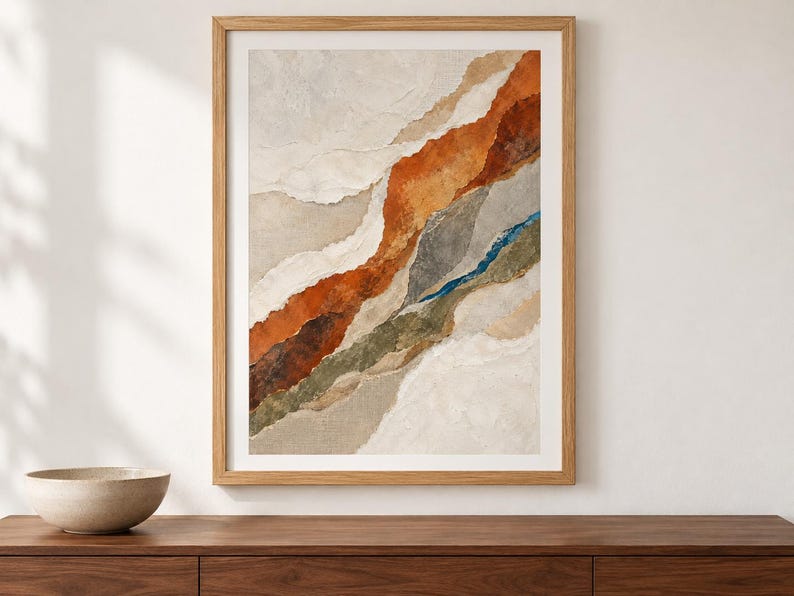 May include: A framed wall art print featuring an abstract composition of layered, torn-paper style shapes in shades of burnt orange, olive green, slate gray, and cream, set within a light-toned wooden frame with a clean, rectangular border.