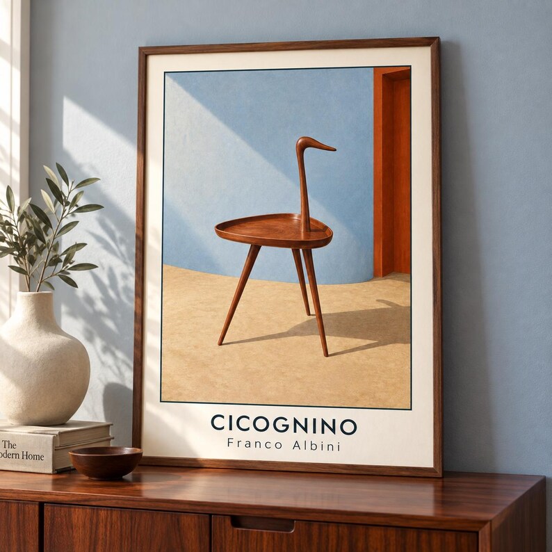 May include: A framed wall art print featuring a brown wooden three-legged side table with a bird-like silhouette. The print includes the text CICOGNINO and Franco Albini at the bottom, set against a background of a blue wall and tan floor.