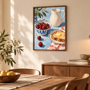 May include: A framed oil painting depicting a still life scene on a blue surface. The artwork features a white pitcher, a bowl filled with red cherries, two loose cherries, and a slice of toasted bread topped with a pat of yellow butter.