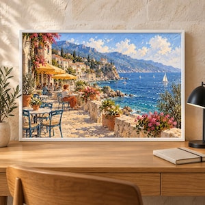 May include: A framed landscape painting depicting a coastal Mediterranean scene with a seaside terrace, outdoor dining tables, yellow umbrellas, potted pink flowers, and a view of the blue ocean with sailboats under a bright, sunny sky.