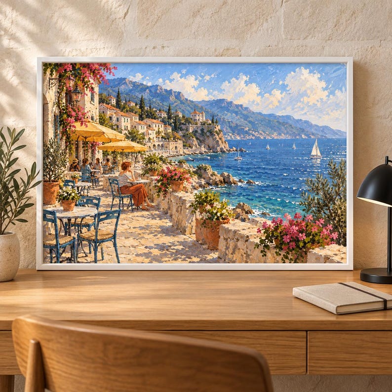 May include: A framed landscape painting depicting a coastal Mediterranean scene with a seaside terrace, outdoor dining tables, yellow umbrellas, potted pink flowers, and a view of the blue ocean with sailboats under a bright, sunny sky.