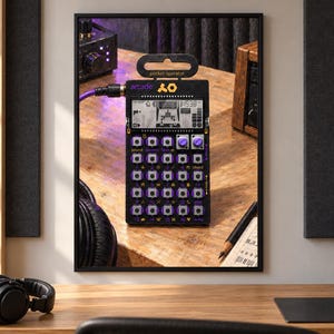 May include: A black pocket operator arcade synthesizer featuring a digital display, purple circular buttons, and a grid of sixteen square keys. The device is labeled with the text pocket operator and arcade, and it is connected to a purple audio cable.