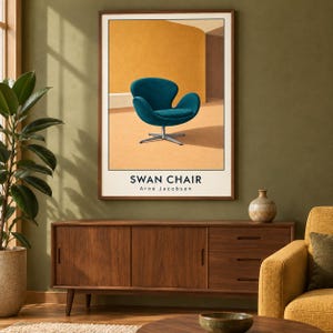 May include: A framed wall art print featuring a teal Swan chair on a light orange background. The text SWAN CHAIR and Arne Jacobsen is printed in black at the bottom of the print. The artwork is displayed in a thin brown wooden frame.