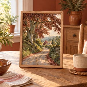 Puede incluir: Una impresi&oacute;n rectangular enmarcada que presenta una pintura de paisaje de un camino de tierra que serpentea a trav&eacute;s de una escena rural con un gran &aacute;rbol con follaje oto&ntilde;al, muros de piedra y una casa distante bajo una luz suave.