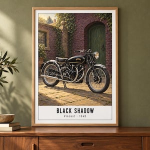 Peut inclure: Une affiche encadr&eacute;e repr&eacute;sentant une moto noire vintage gar&eacute;e sur une terrasse en pierre devant un b&acirc;timent en briques avec une porte verte. Le texte en bas indique BLACK SHADOW Vincent - 1948 dans une police noire sans empattement.