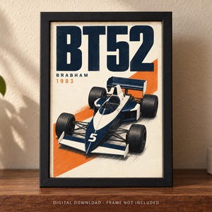 May include: A framed poster featuring a blue and white Brabham BT52 Formula One race car with the number 5 on the nose. The text BT52, BRABHAM, and 1983 are printed in bold blue and orange colors against a cream background with an orange diagonal stripe.