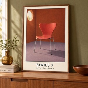 May include: A framed art print featuring a red Series 7 chair by Arne Jacobsen. The chair is set against a deep orange wall with a circular window and a purple floor. The text Series 7 and Arne Jacobsen is printed in black at the bottom.