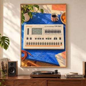 May include: A framed art print depicting a vintage Roland TR-707 Rhythm Composer drum machine on a bright blue table. The scene includes a potted plant, a striped mug, and oranges. The drum machine features a digital display, sliders, and buttons.
