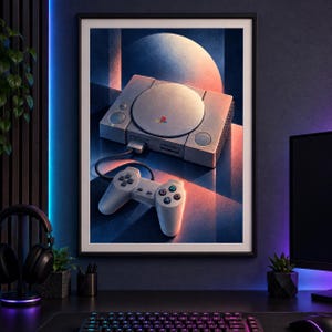 May include: A framed art print featuring a gray retro video game console with a circular disc lid and a matching wired controller. The console displays a colorful logo on the top surface. The artwork uses deep blue and warm orange lighting effects.