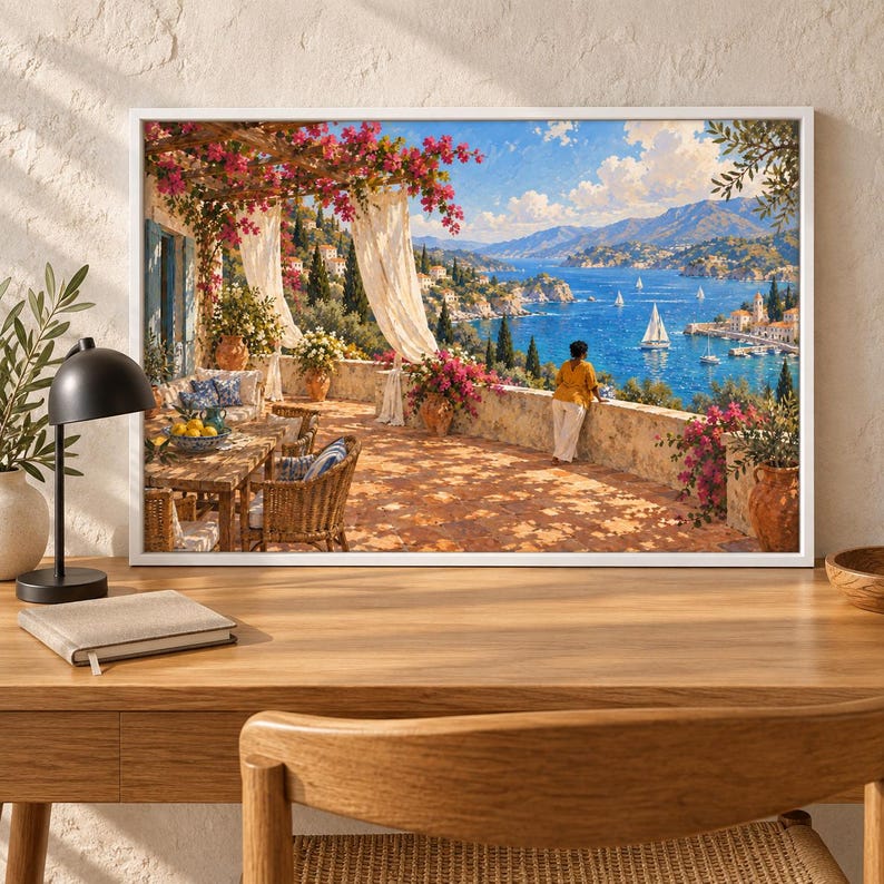 May include: A framed wall art print depicting a sunlit Mediterranean terrace with a stone floor, wicker furniture, and vibrant pink bougainvillea flowers. A person in a yellow shirt stands by a stone wall overlooking a blue bay with sailboats.