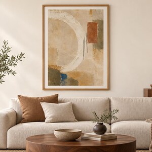 Puede incluir: Una impresi&oacute;n de arte mural abstracto enmarcada que presenta una gran pincelada circular blanca, un bloque rectangular de terracota y tonos tierra apagados de beige, verde oliva y azul profundo sobre un fondo texturizado, en un marco de madera clara.