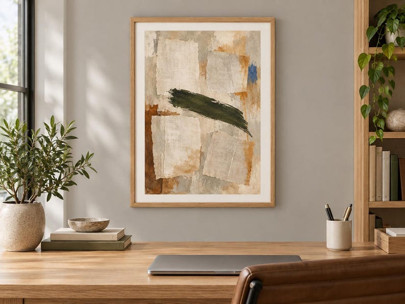 May include: A framed abstract wall art print featuring layered rectangular shapes in shades of beige, cream, and brown, accented by a bold, horizontal dark green brushstroke across the centre and a small patch of bright blue in the upper corner.