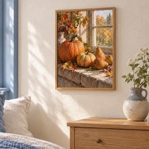May include: A rectangular wall art print in a light wood frame depicting a still life scene of a large orange pumpkin, a smaller striped pumpkin, and several pears resting on a stone ledge with autumn leaves and a view of trees outside.