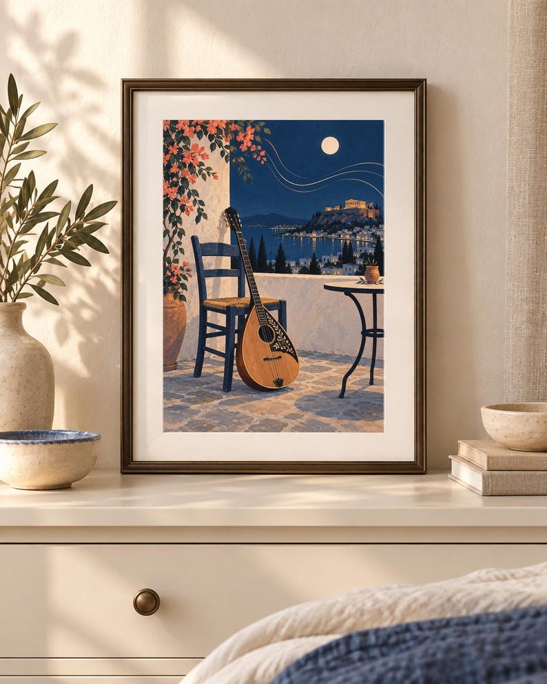 Pu&ograve; includere: Una stampa d'arte incorniciata raffigurante una scena notturna su un balcone con un bouzouki in legno appoggiato a una sedia blu. La vista include una terrazza in pietra, un tavolino, fiori arancioni, una costa illuminata e la luna piena.