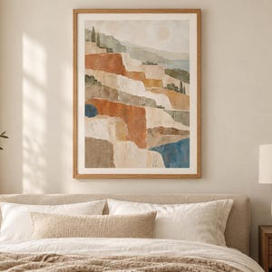 Op de afbeelding: Een ingelijste wandkunstprint met een landschapsillustratie van gelaagde, terrasvormige heuvels in tinten terracotta, cr&egrave;me en gedempt groen, geaccentueerd door donkerblauwe vlakken en slanke cipressen onder een bleke, zachte zon.