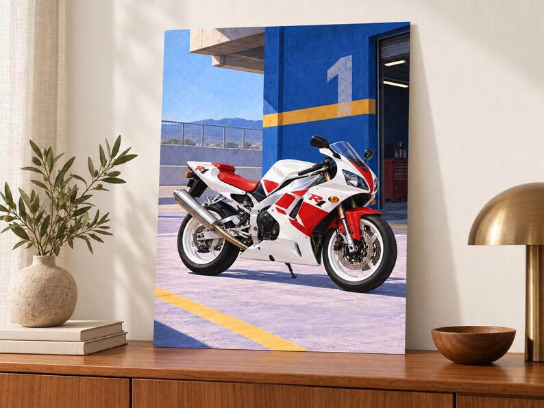 May include: A white and red sport motorcycle with R1 branding parked in front of a blue wall featuring a large number 1. The motorcycle has a silver exhaust pipe, white wheels, and a sleek fairing design, positioned on a paved surface.