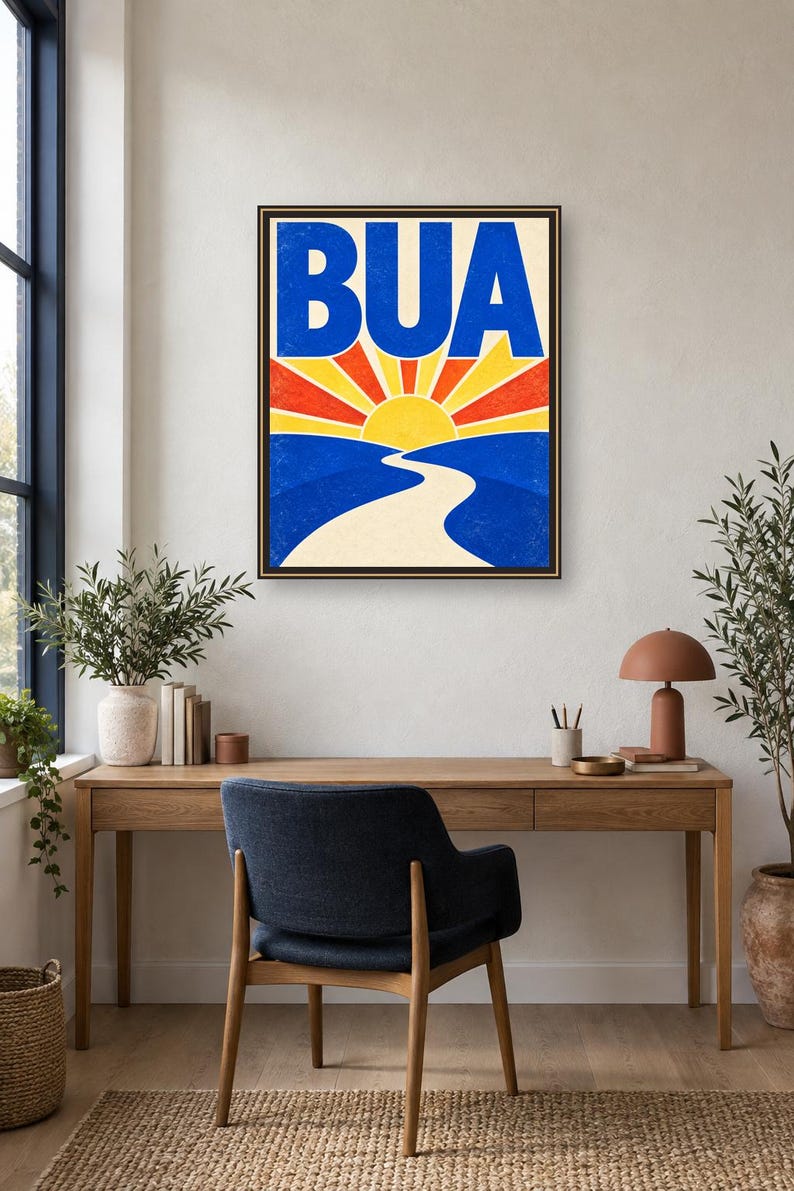 May include: A framed rectangular wall art print featuring the text BUA in large blue letters above a stylized yellow sun with red and yellow rays. Below the sun, a winding beige path leads through blue hills, creating a vibrant landscape scene.