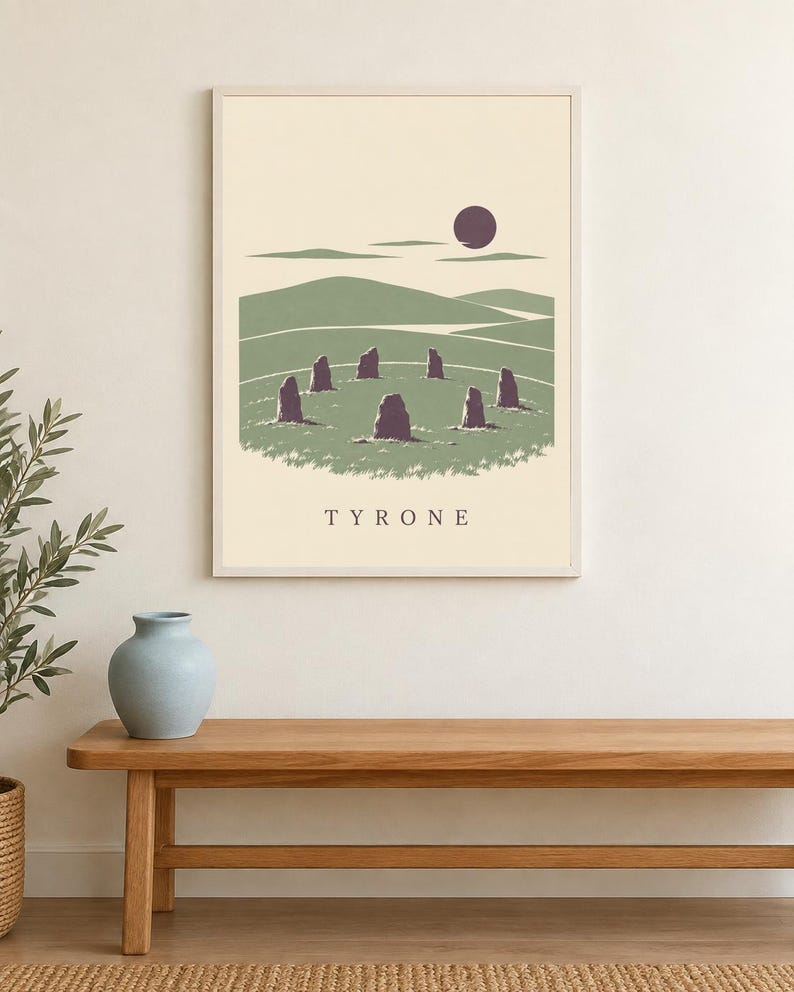 May include: A rectangular wall art print in a light frame featuring a graphic illustration of a stone circle in a green landscape under a dark purple sun. The word TYRONE is printed in capital letters at the bottom of the cream-colored background.