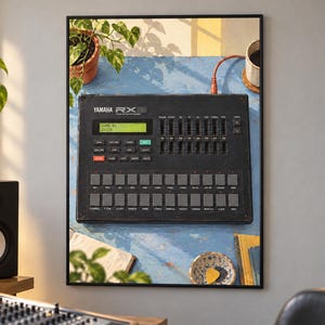 Pode incluir: Uma bateria eletr&ocirc;nica Yamaha RX15 preta com uma tela LCD verde exibindo "SONG 01" e "J=120", uma s&eacute;rie de faders verticais e uma grade de pads de borracha quadrados rotulados com nomes de v&aacute;rios instrumentos de percuss&atilde;o.