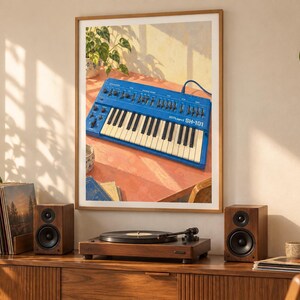 May include: A framed wall art print featuring a blue Roland SH-101 synthesizer on a table. The synthesizer has a keyboard with white and black keys, numerous knobs, and sliders. The print is displayed in a room with wooden furniture, speakers, a record player, and green plants.