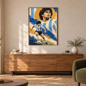 May include: A rectangular wall art print featuring a portrait and an action shot of Diego Maradona playing soccer. The artwork uses a color palette of blue, white, and yellow, depicting the athlete in a light blue and white striped jersey.