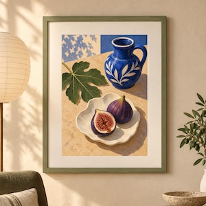 May include: A framed wall art print featuring a vibrant blue ceramic pitcher with white leaf patterns, a single green fig leaf, and a white scalloped dish holding one whole purple fig and one halved fig with a visible red interior on a tan surface.