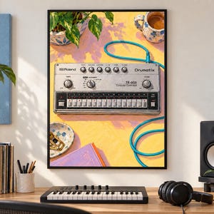 Pu&ograve; includere: Una stampa d'arte incorniciata che mostra un'illustrazione dall'alto di una drum machine Roland TR-606 Drumatix argentata su una superficie gialla. Il dispositivo presenta manopole nere, un sequencer a passi e un cavo blu brillante. Sono presenti una pianta, una tazza e una ciotola.