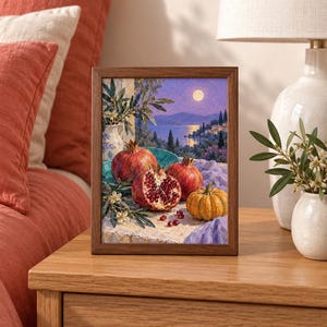Op de afbeelding: Een ingelijste rechthoekige print met een olieverfschilderij van granaatappels en een kleine pompoen op een stenen richel. De sc&egrave;ne bevat een blauwe kom, een witte kan en een kustlandschap bij schemering met een volle maan boven het water.
