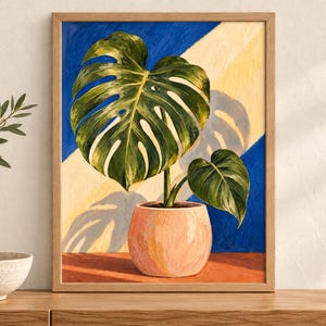 Puede incluir: Un cuadro enmarcado de una planta monstera en una maceta color melocot&oacute;n claro. La planta tiene hojas verdes grandes y divididas. El fondo presenta una divisi&oacute;n diagonal en azul oscuro y amarillo p&aacute;lido, con una sombra proyectada en la zona amarilla.