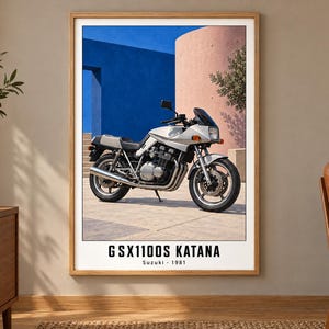 Puede incluir: Una l&aacute;mina enmarcada que muestra una motocicleta Suzuki GSX1100S Katana plateada aparcada sobre una superficie pavimentada. El fondo muestra una pared azul brillante y una estructura rosa curva. El texto GSX1100S KATANA Suzuki 1981 aparece debajo.