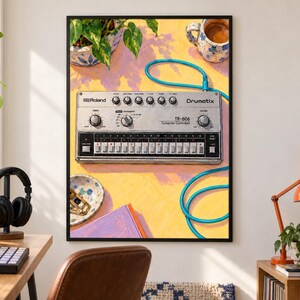 Pu&ograve; includere: Una stampa artistica incorniciata che raffigura una drum machine argentata Roland TR-606 Drumatix con un cavo blu brillante collegato sulla parte superiore. Il dispositivo &egrave; posto su uno sfondo giallo vivace con una tazza decorata e un libro viola.